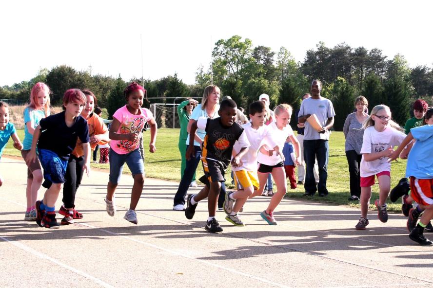 Children running on a playground, while parents watch from the side